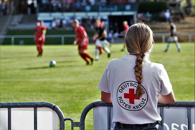 zu sehen ist eine DRK-Helferin bei einem Sanitätsdienst auf dem Fußballplatz