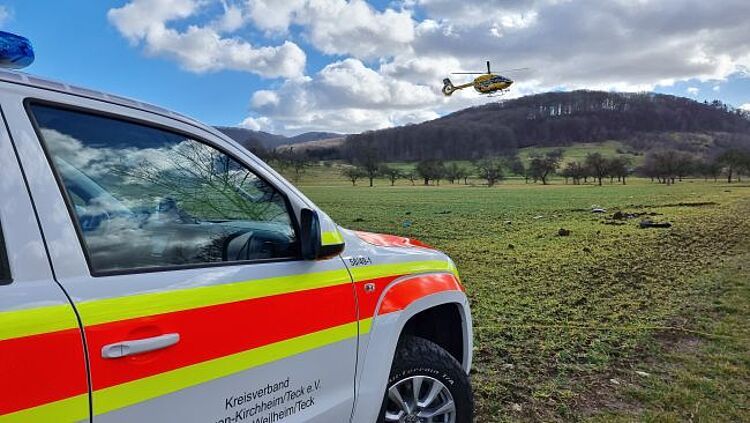 zu sehen ist das Helfer-vor-Ort Fahrzeug und im Hintergrund ein Rettungshubschrauber im Landeanflug